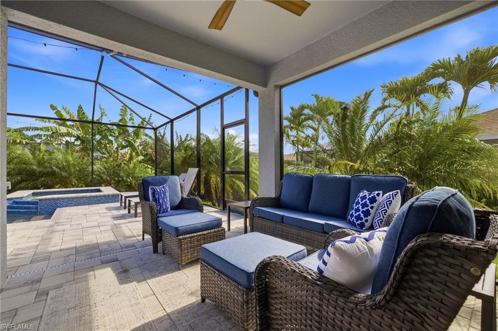 Screened lanai featuring a ceiling fan, tiled flooring, built-in spa, and tropical landscaping