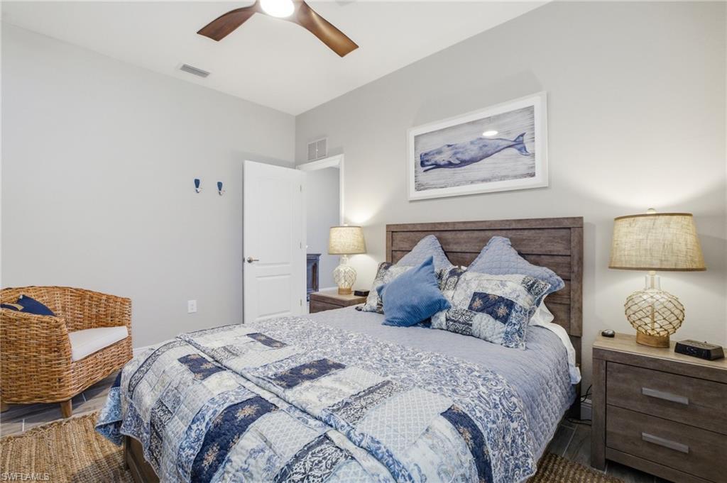 Bedroom featuring a wood-finish headboard, matching nightstands, and a ceiling fan with integrated lighting