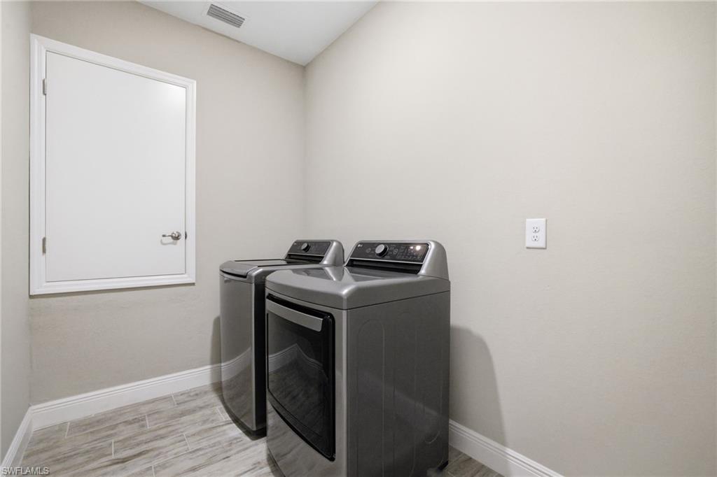 Laundry area featuring wood-finish tile flooring, light neutral wall paint, and white baseboards