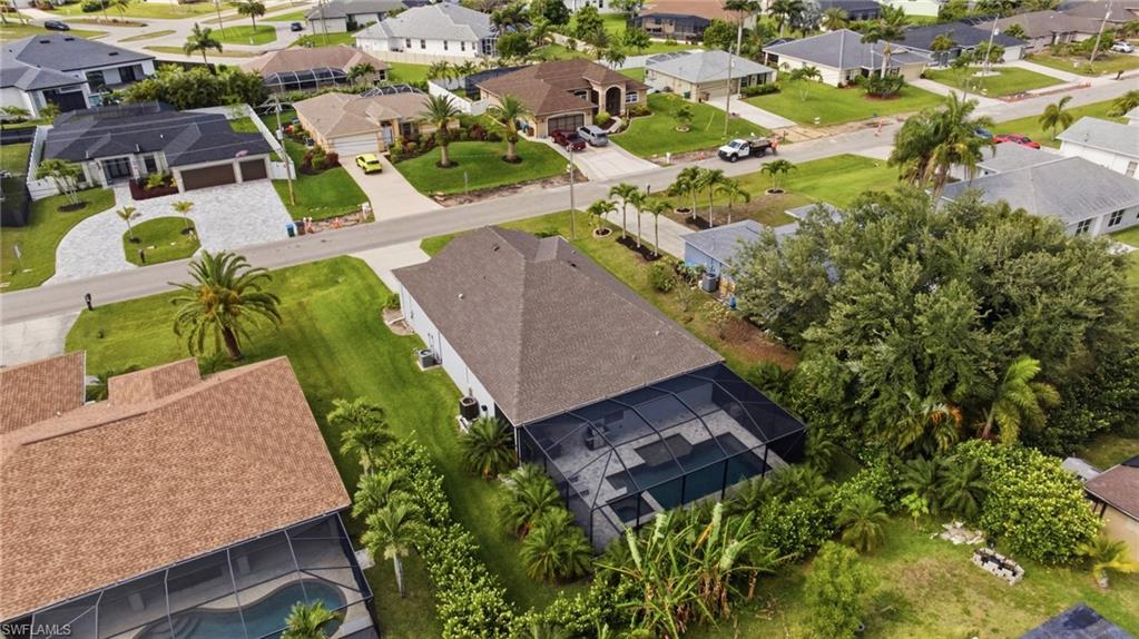 Property featuring a screened-in pool enclosure, mature tropical landscaping, and a substantial lot