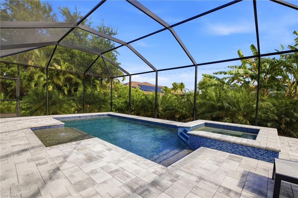 Screened lanai featuring a swimming pool, integrated spa with mosaic tile, and paver decking