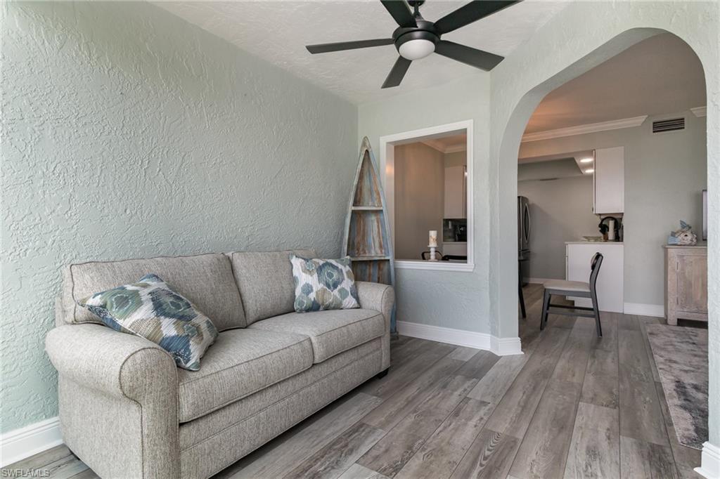 Living room featuring arched walkways, a textured wall, visible vents, and a ceiling fan