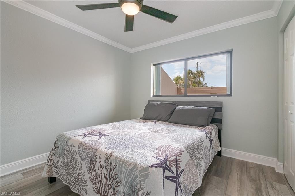 Bedroom with baseboards, wood finished floors, and crown molding