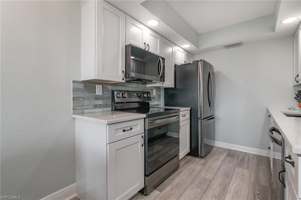 Kitchen featuring decorative backsplash, visible vents, baseboards, appliances with stainless steel finishes, and light wood-style floors