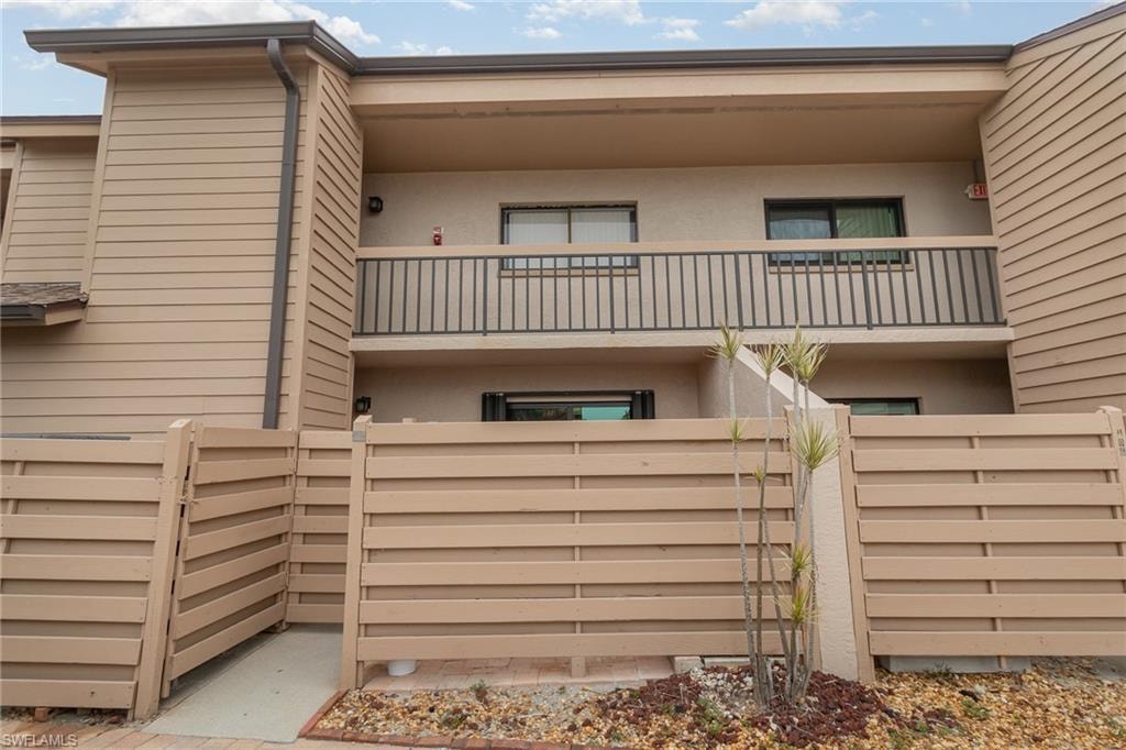 Rear view of property with a balcony, stucco siding, and fence