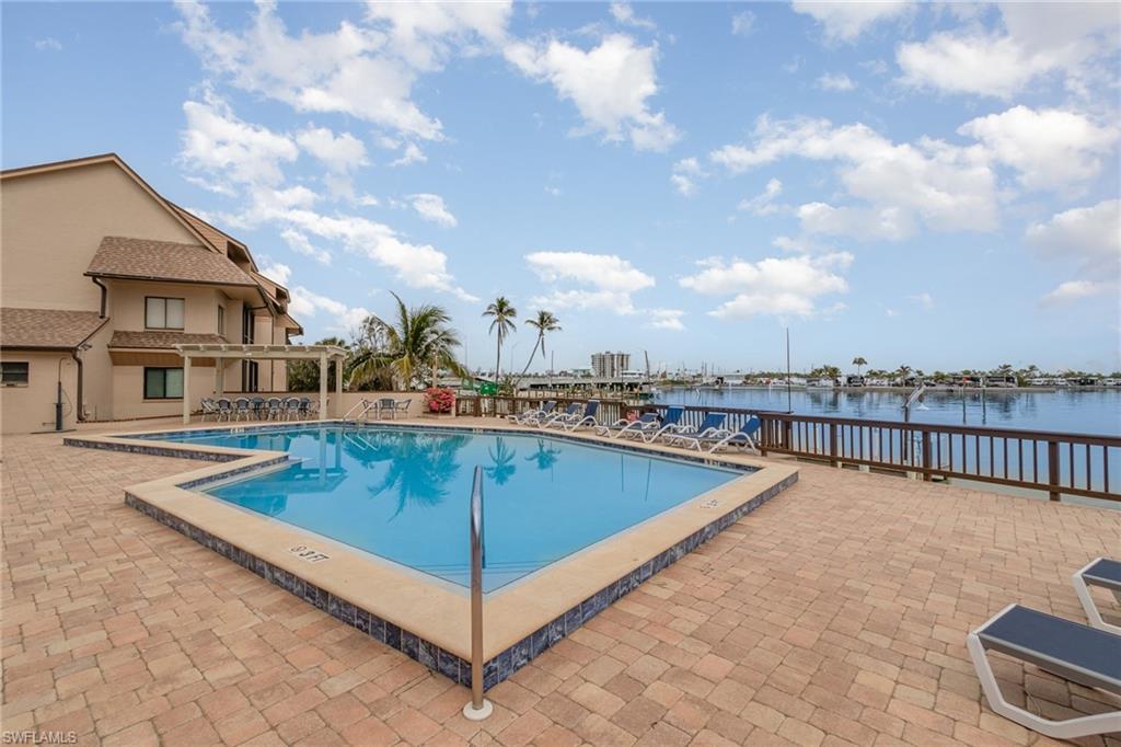 Community pool with a water view, a pergola, and a patio area