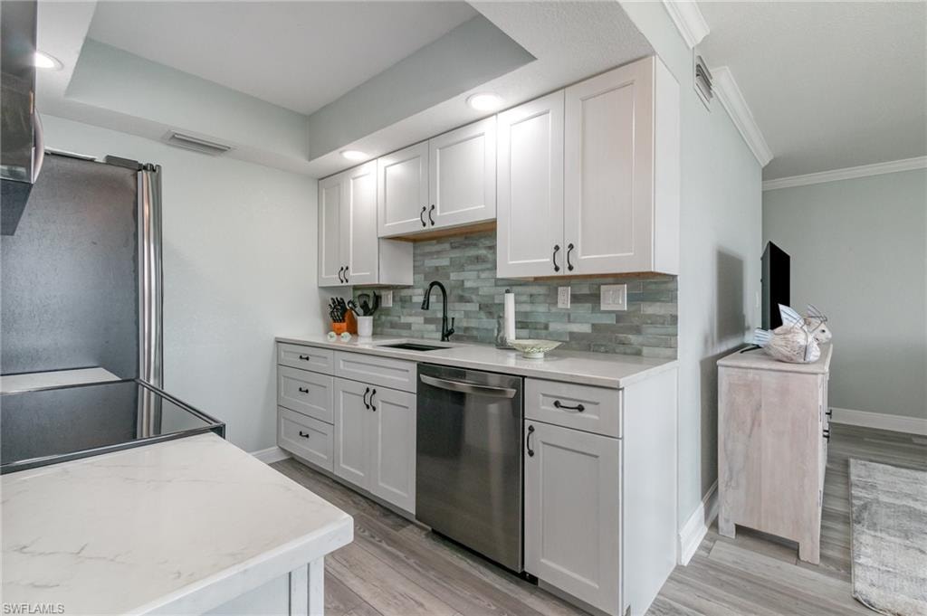 Kitchen featuring a sink, tasteful backsplash, appliances with stainless steel finishes, and light wood finished floors