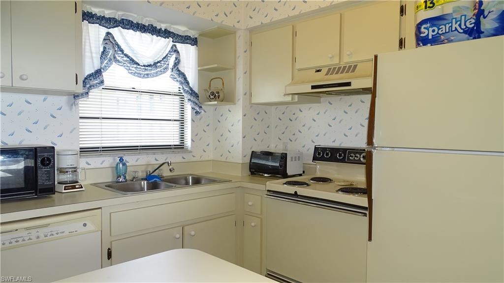 Kitchen featuring white cabinetry, dual basin sink, white dishwasher, electric range with oven, and a refrigerator