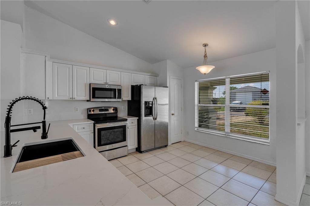 Kitchen featuring white cabinetry, stainless steel appliances, a black sink with a matte black faucet, light countertops, and tile flooring