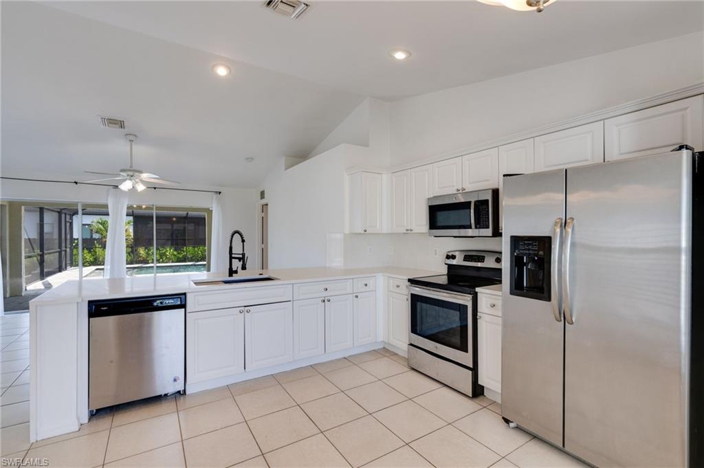 White kitchen cabinetry with stainless steel appliances, a white tile backsplash, and light-toned countertops