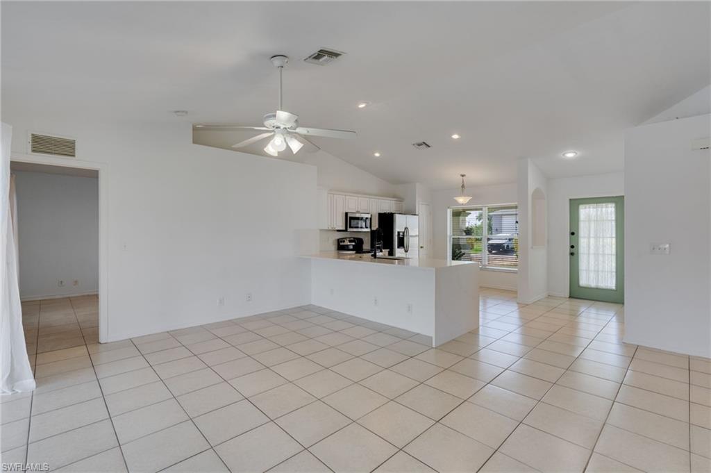 Expansive open-concept room featuring tile flooring, vaulted ceilings, and recessed lighting