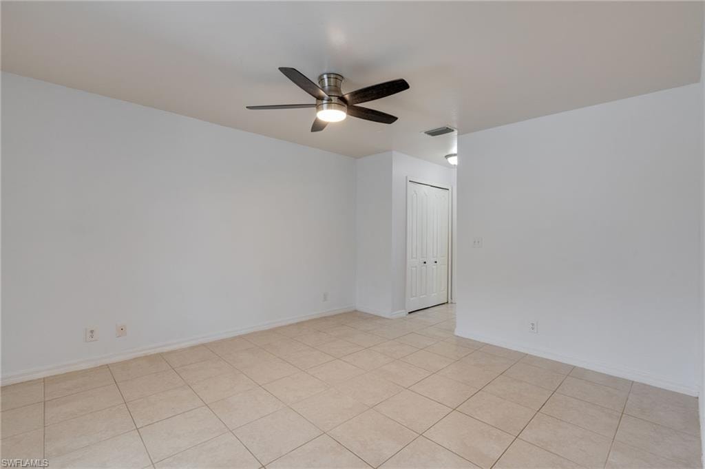 Spacious room featuring tile flooring, a ceiling fan with integrated lighting, and neutral wall tones