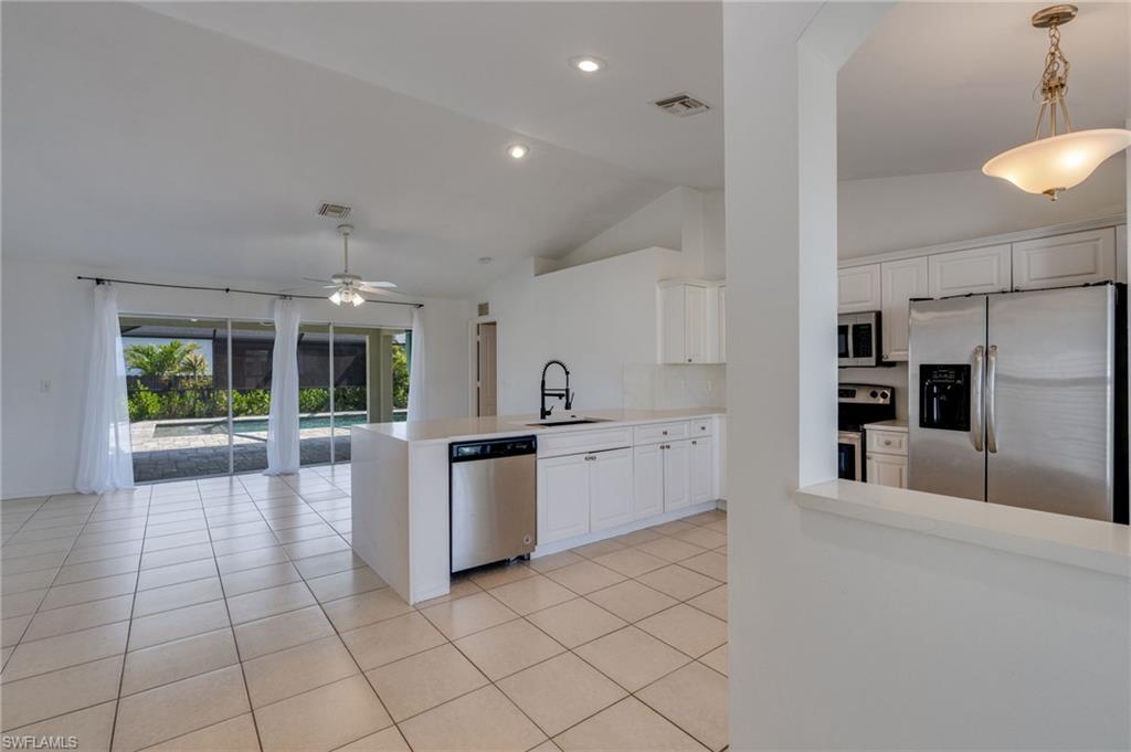 Open-concept living area featuring light-toned tile flooring, vaulted ceilings, and recessed lighting