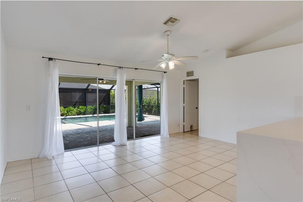 Bright interior room featuring light-toned tile flooring, direct access to a screened-in patio, and an outdoor swimming pool