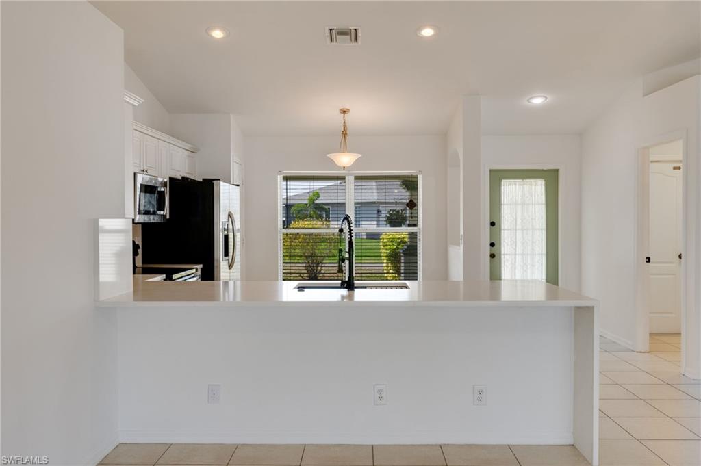 Kitchen featuring a spacious peninsula with a white countertop, recessed lighting, and a window with blinds