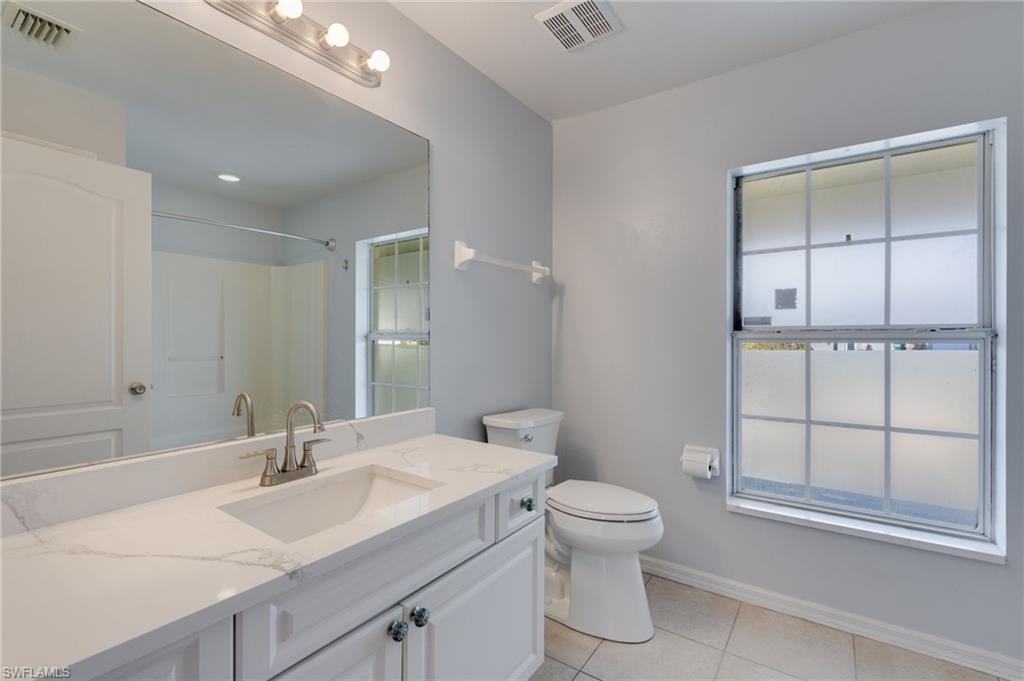 Bathroom featuring a single vanity with stone-finish countertop, undermount sink, and brushed nickel faucet