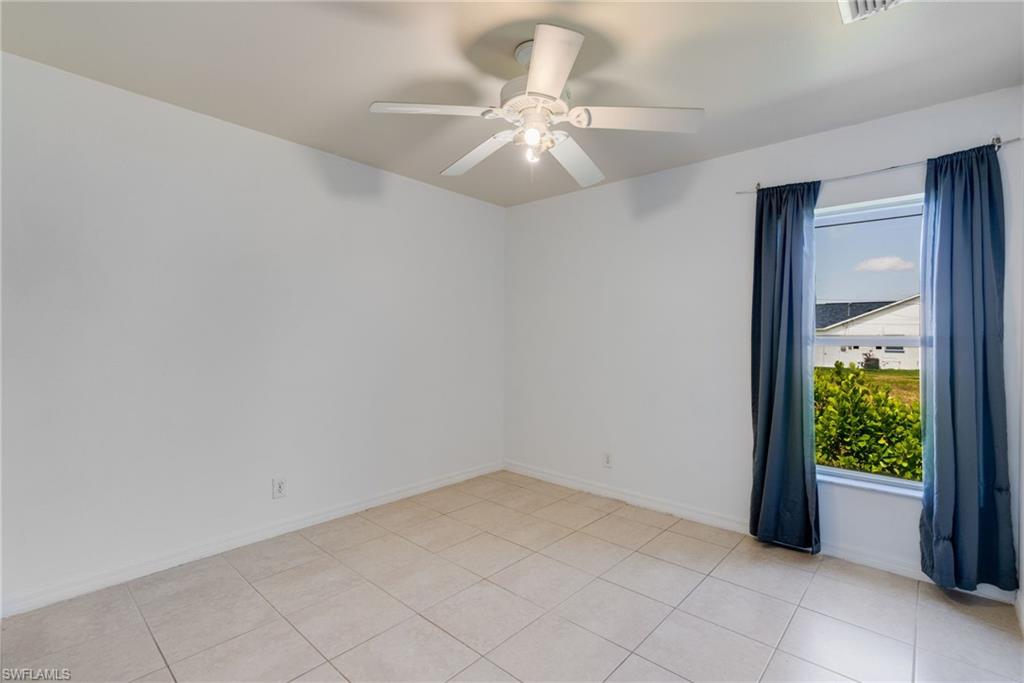 Bright interior space featuring light-toned tile flooring, white walls, and a ceiling fan with integrated lighting