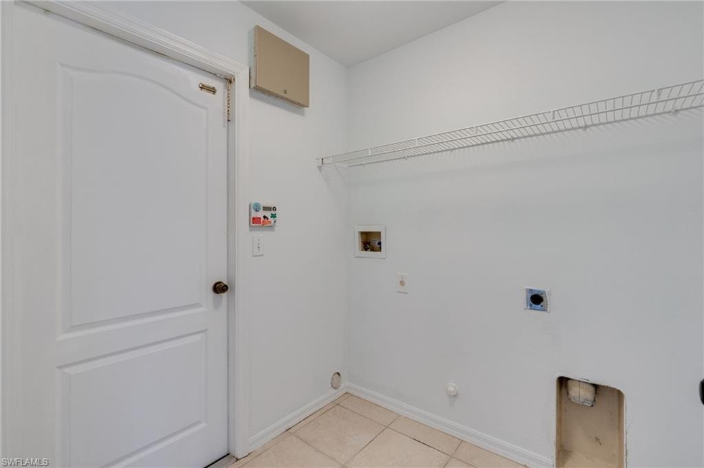 Utility area with ceramic tile flooring, a paneled door, wall-mounted wire shelving, and appliance hookups