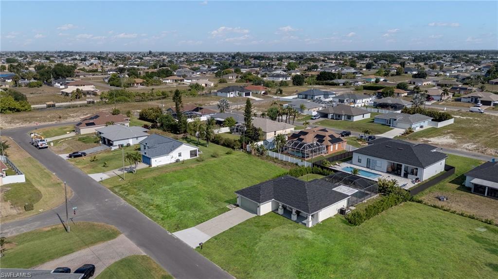 Expansive lot featuring a newly constructed residence with a dark shingle roof, a paved driveway, and an attached garage
