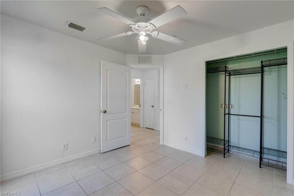 Spacious room featuring tile flooring, a ceiling fan with integrated lighting, and an open closet space with a built-in metal shelving system