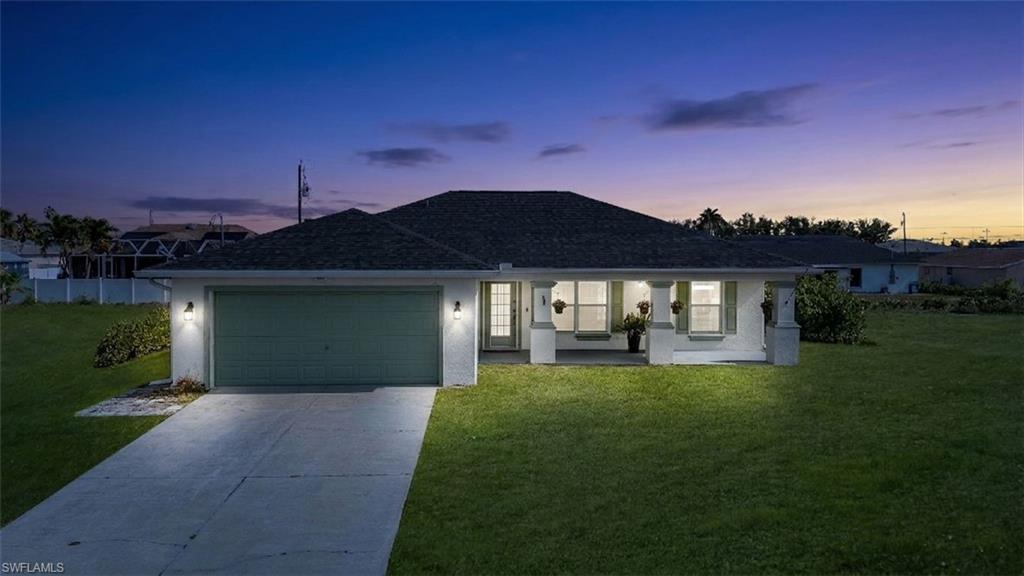 Single-story residence featuring a two-car garage, a covered front porch with pillar accents, and a well-maintained lawn