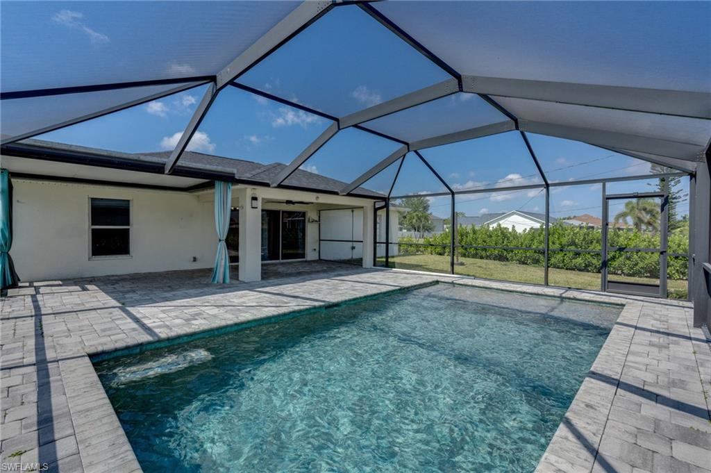 Screen-enclosed pool area featuring a rectangular pool with integrated steps, surrounded by a paver patio