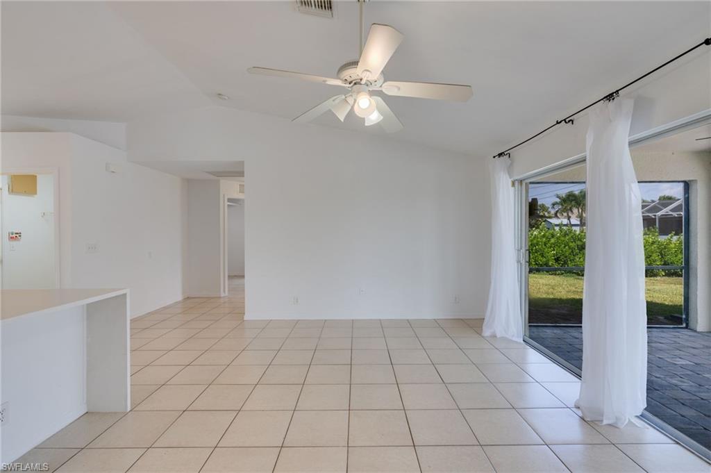 Open-concept interior featuring light-colored tile flooring, vaulted ceilings, and a ceiling fan