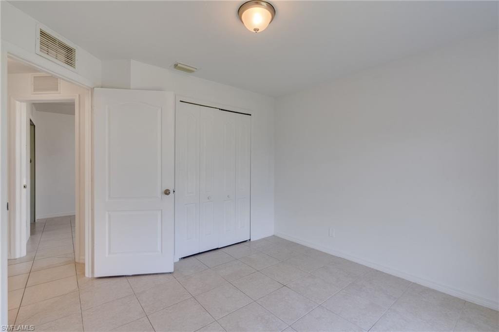Neutral-toned tile flooring throughout this room, featuring a built-in closet with bifold doors