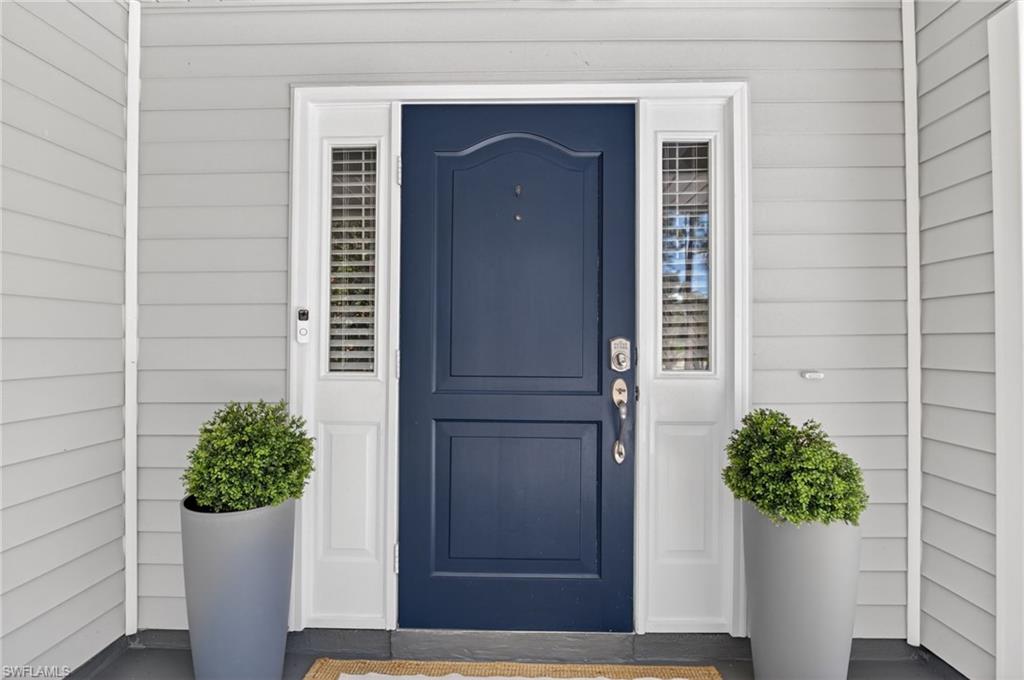 Navy blue paneled entry door with sidelights, white trim, and light grey horizontal siding
