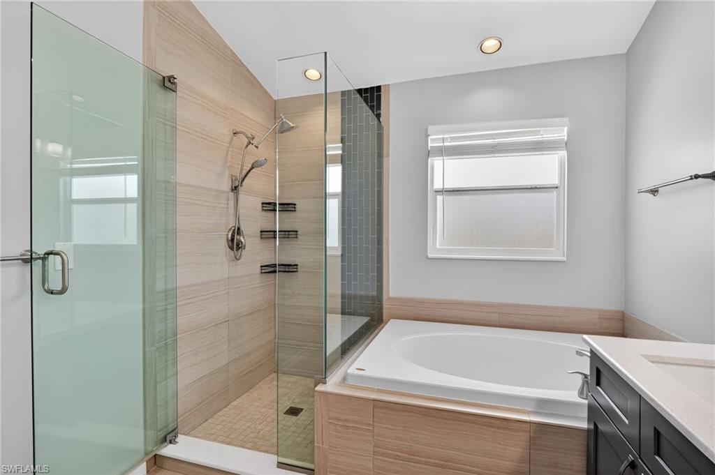 Sleek bathroom featuring a spacious walk-in shower with glass enclosure, light-toned horizontal tile, and a rainfall showerhead