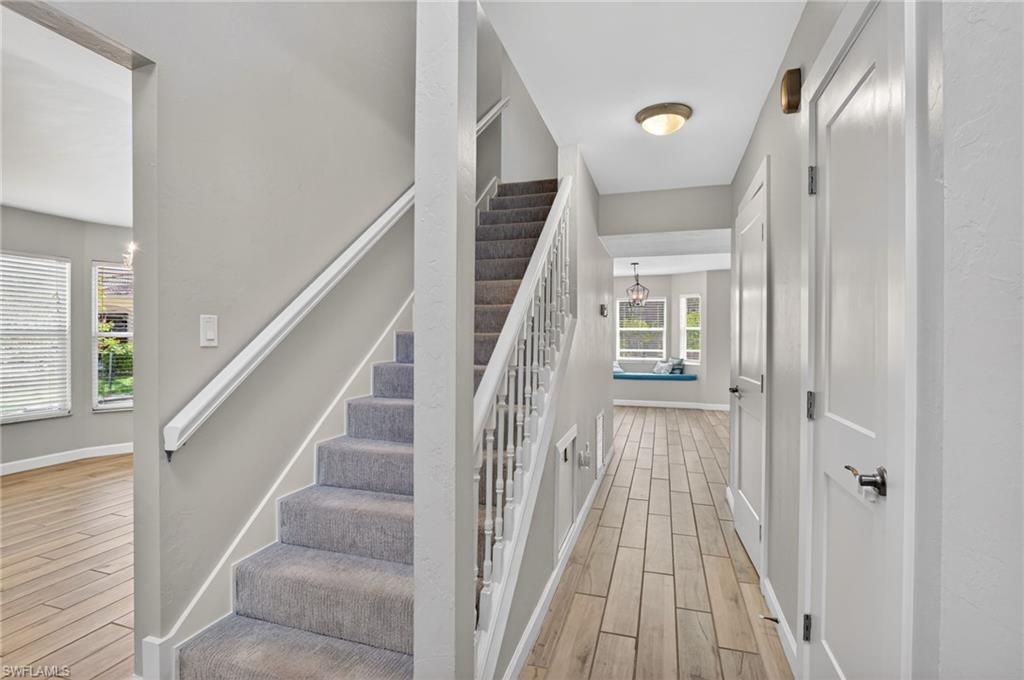 Entryway featuring wood-finish flooring, a carpeted staircase with white balusters, and a recessed window seat