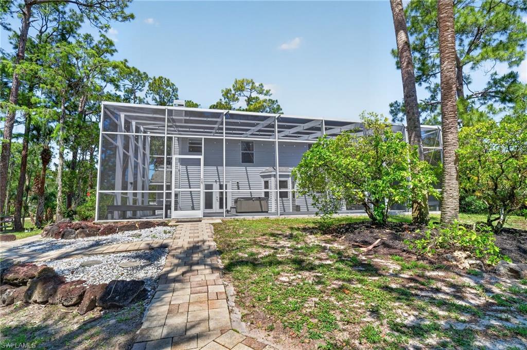 Screened enclosure with dual entry doors, encompassing a rear exterior with light gray siding