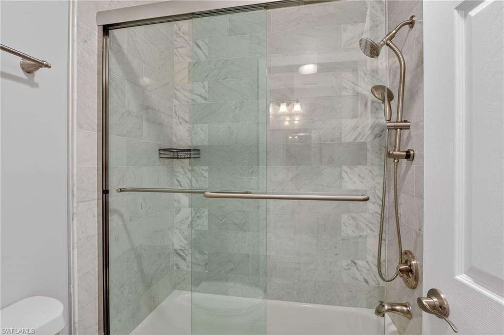 Shower-over-tub combination featuring a frameless glass enclosure with brushed nickel hardware