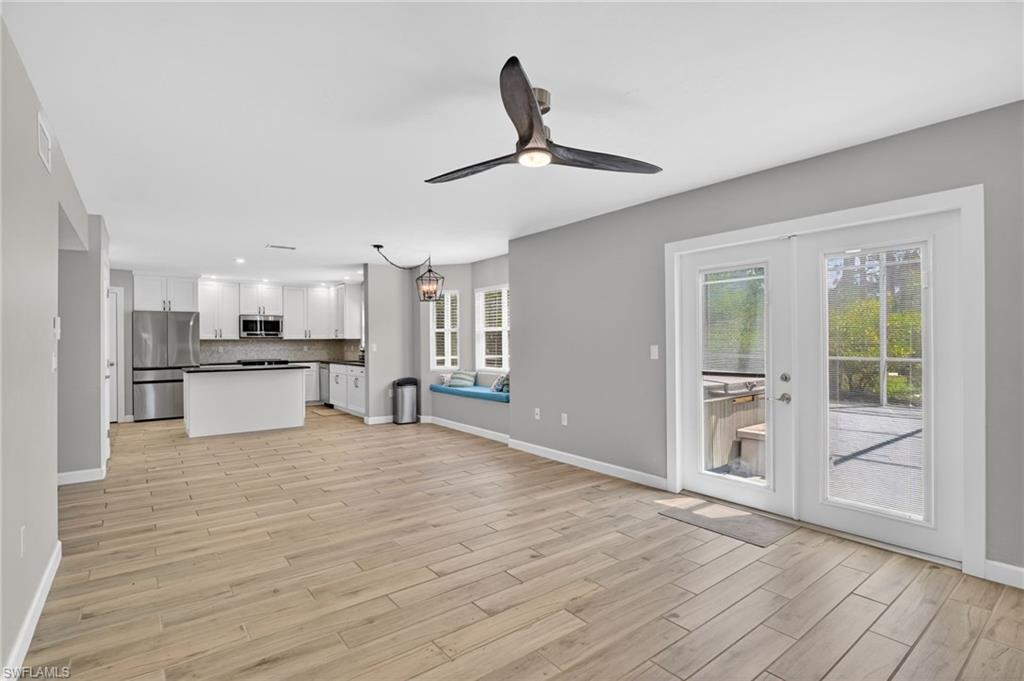 Spacious open-concept living area featuring wood-finish flooring and a contemporary ceiling fan