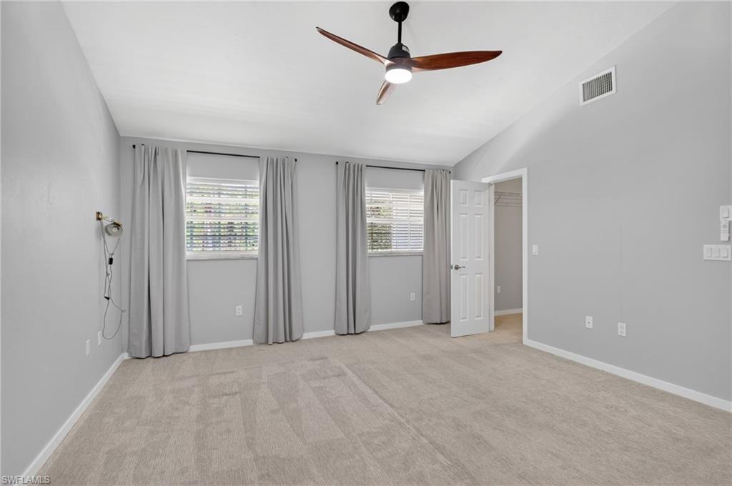 Spacious room featuring vaulted ceilings and neutral-toned carpeting