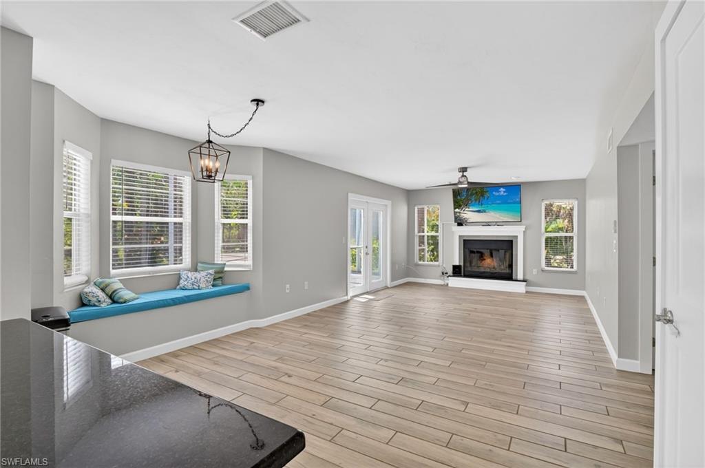 Spacious living area featuring wood-finish flooring, a fireplace with a white mantel, and multiple windows