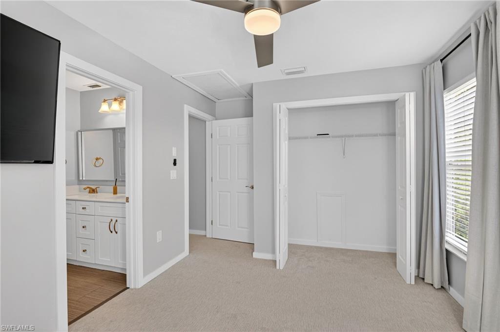 Carpeted room featuring a ceiling fan, a window with blinds and drapes, and a bifold door closet