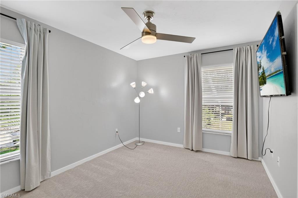 Spacious room featuring neutral carpeting, light gray walls, and white window blinds