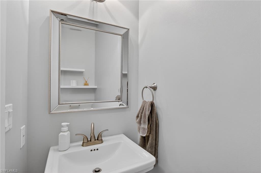 Pedestal sink with a brushed nickel faucet and an ornate framed mirror