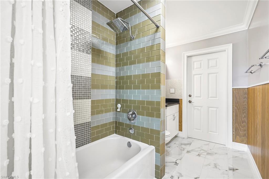 Bathroom featuring a combined tub and shower with a rainfall showerhead, subway tile surround, and mosaic tile accent