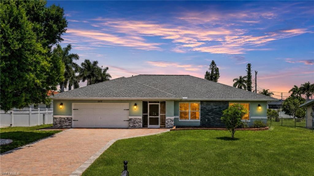 Single-story residence featuring a gray shingle roof and a muted green exterior with stone accents
