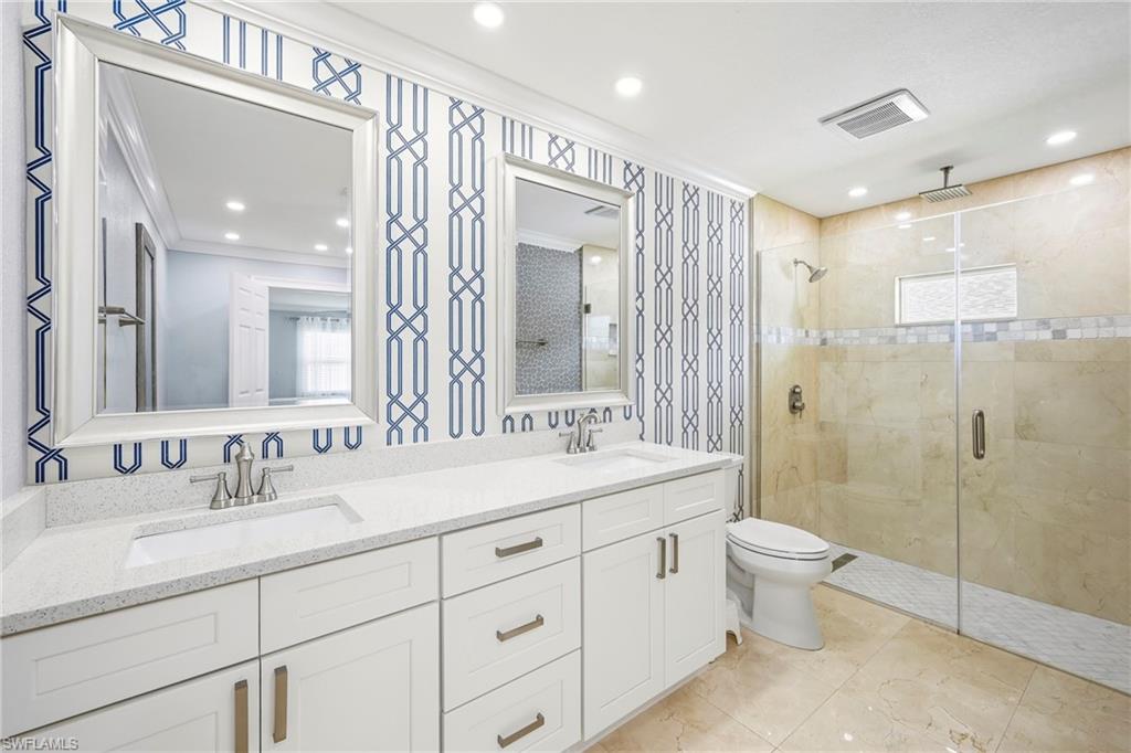 Dual vanity featuring white shaker cabinetry, quartz countertops, and brushed nickel fixtures