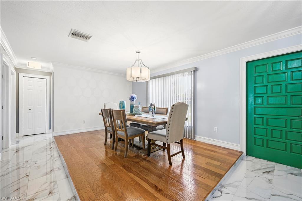 Dining area featuring a contemporary chandelier, hardwood flooring, and a large window with vertical blinds