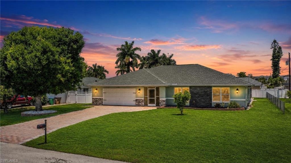 Single-story residence featuring a brick paver driveway, an attached two-car garage, and a screened front entry