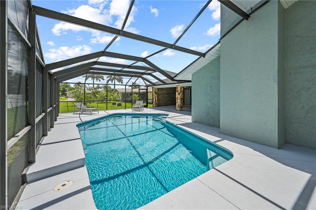 Screened-in swimming pool featuring a curved design and light-colored coping
