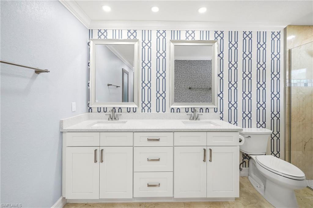 Dual vanity featuring white shaker cabinetry, light-toned countertops, and two framed mirrors