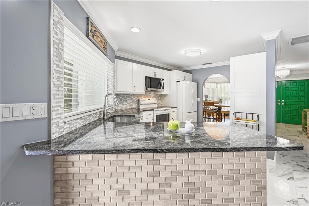 Kitchen featuring a large breakfast bar with a tile facade, granite countertop, and undermount sink