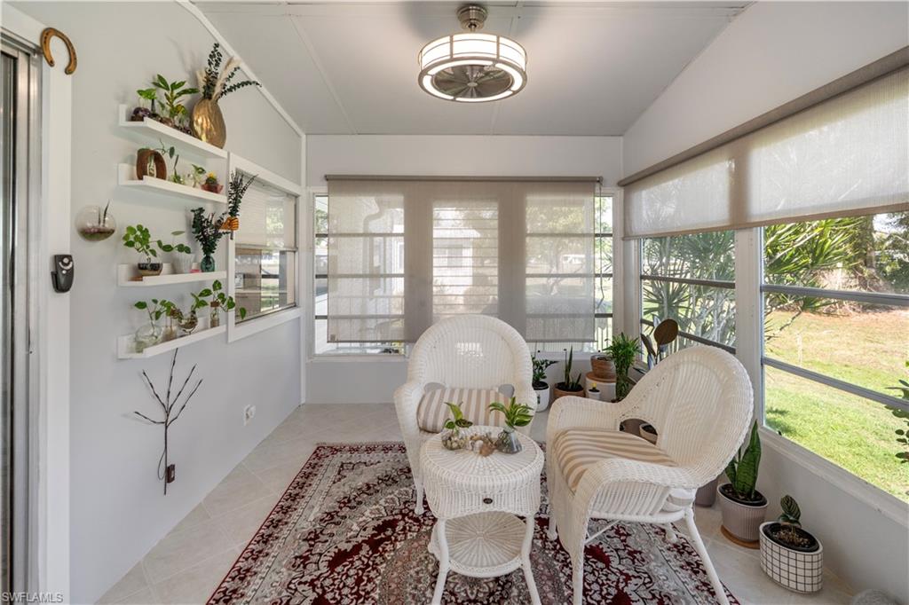 Sunroom featuring multiple windows with roller shades, white tile flooring, and a ceiling fan with integrated lighting