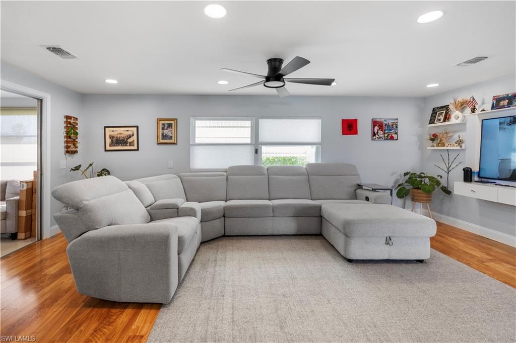 Spacious interior featuring wood-finish flooring, recessed lighting, a contemporary ceiling fan, and light gray wall paint