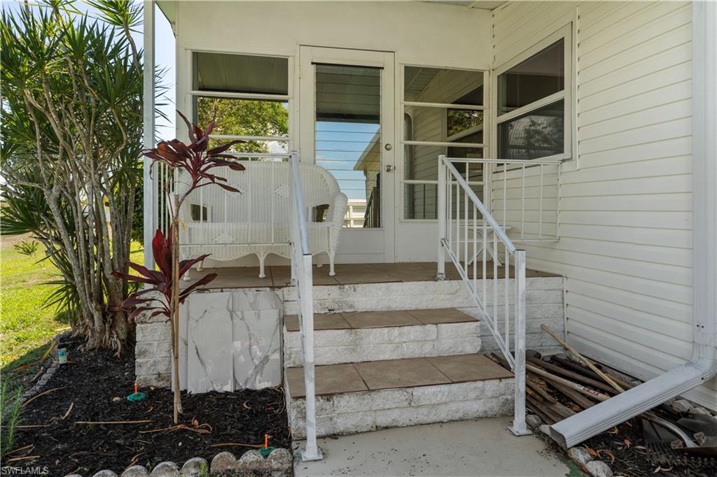Entryway featuring a three-step staircase with a white metal railing, tile treads, and a white siding exterior